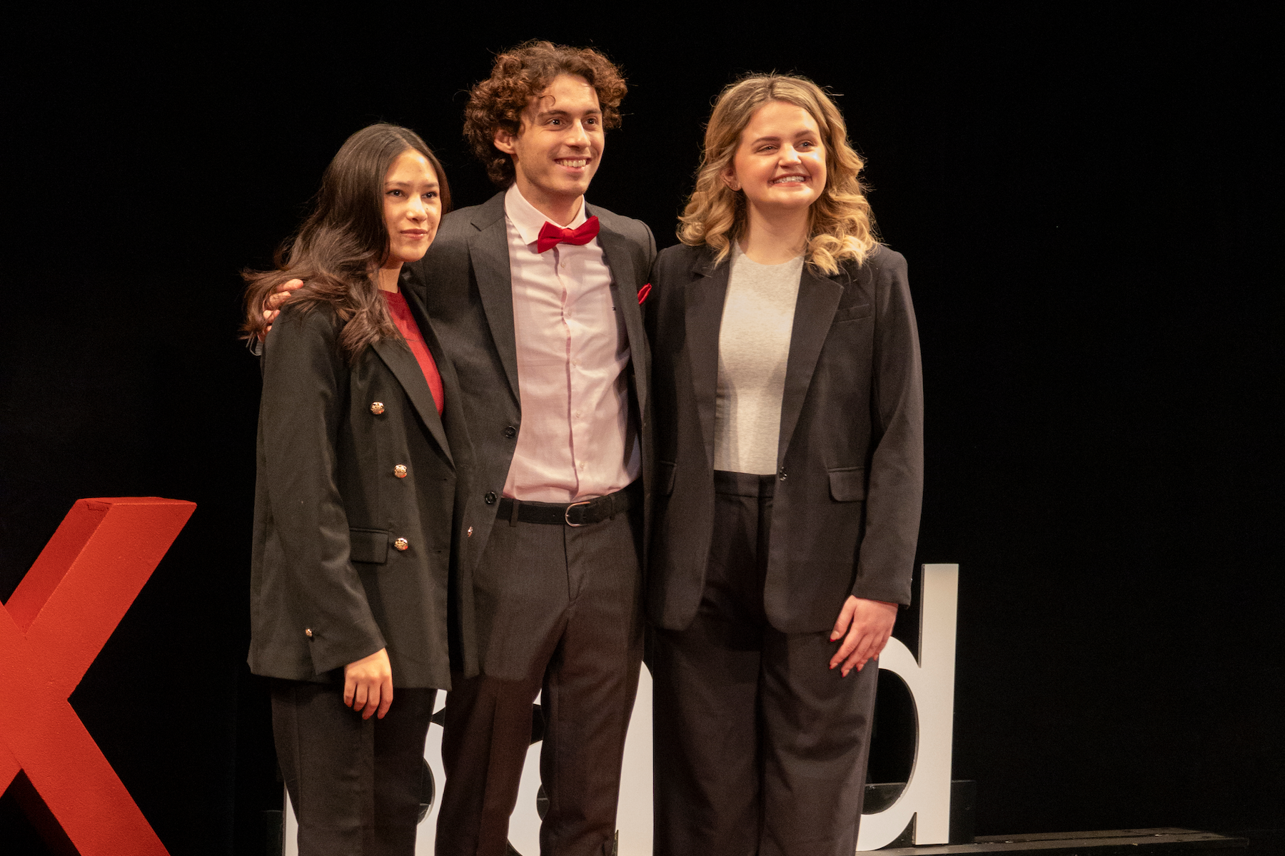 Masoma Shoayb, Thanasis Kostikas, and Emily O'Rourke, leaders of TEDxBard, posing together on the stage