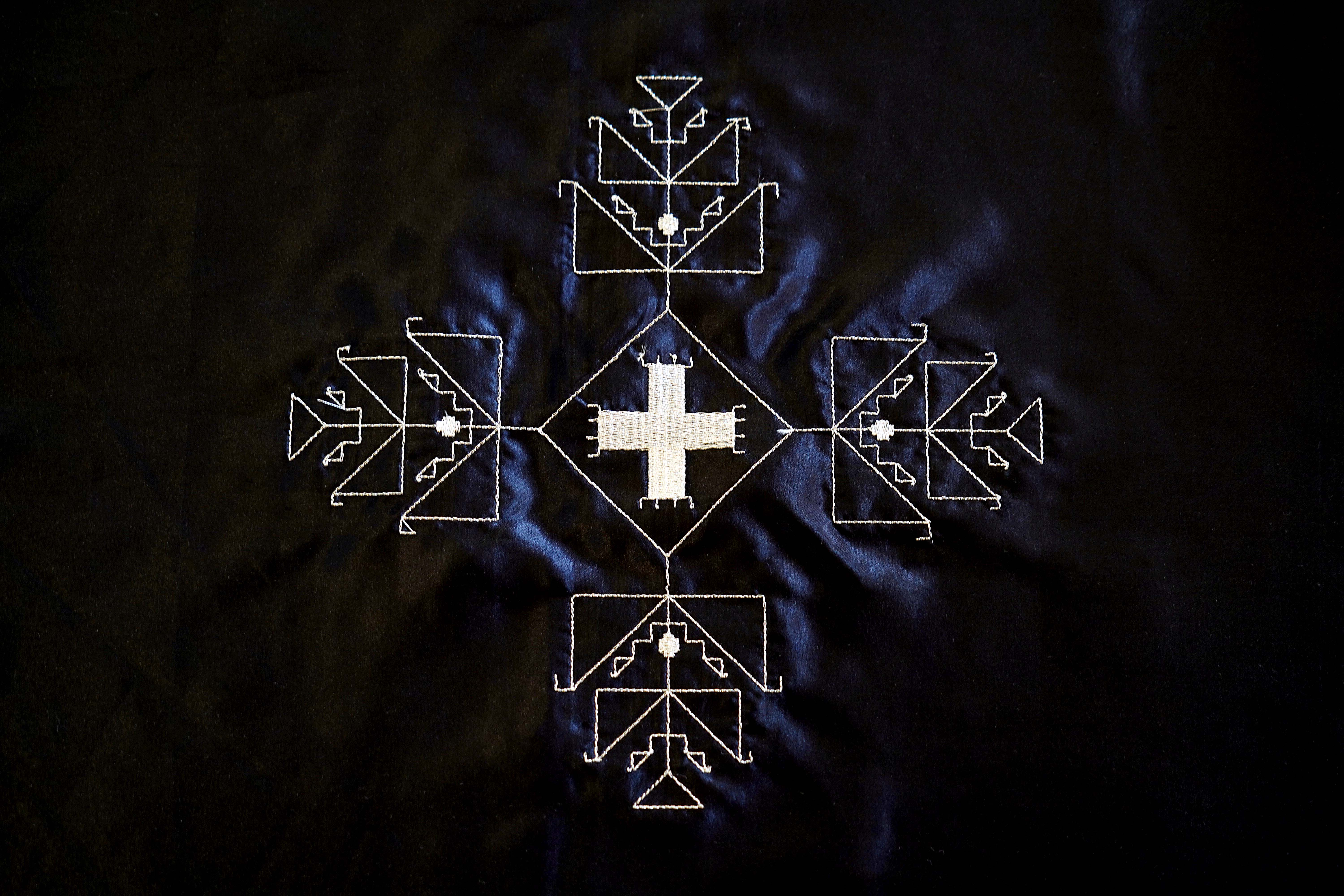 A design in white thread on blue satin, titled Wichahpih'a.