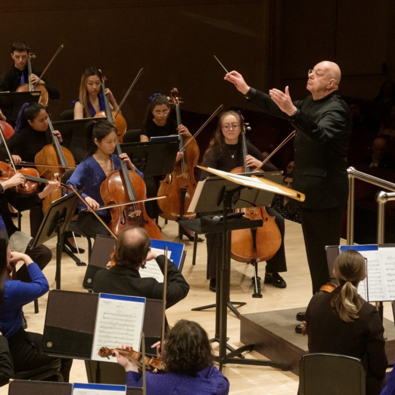 A conductor dressed in all black conducts an orchestra sitting in front of him.; Visit https://ton.bard.edu/events/america