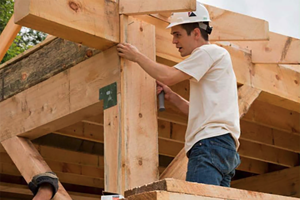 Student helping to construct a wooden building.; Trustee Leader Scholar (TLS) Fair