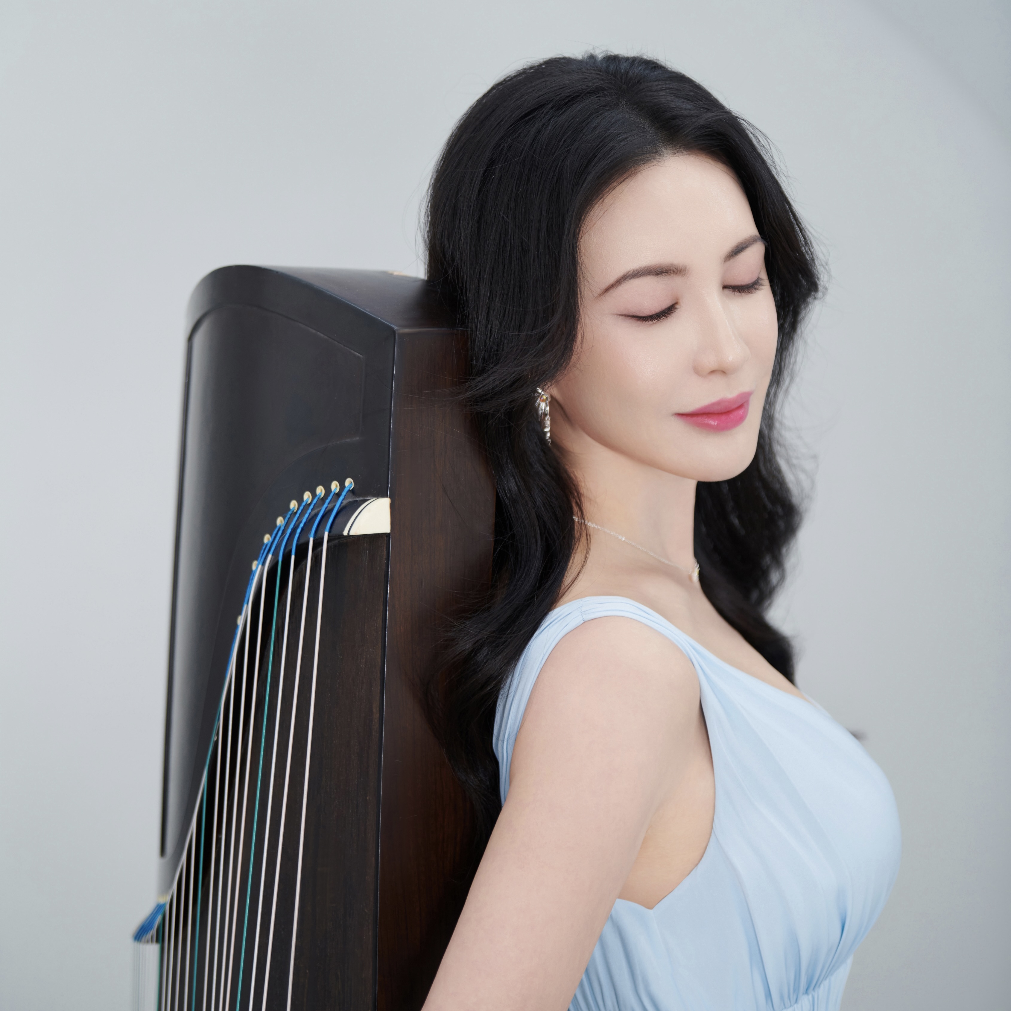 A photo of a musician posing with a string instrument.; Degree Recital: Lucina Yue, guzheng, with Neilson Chen, piano