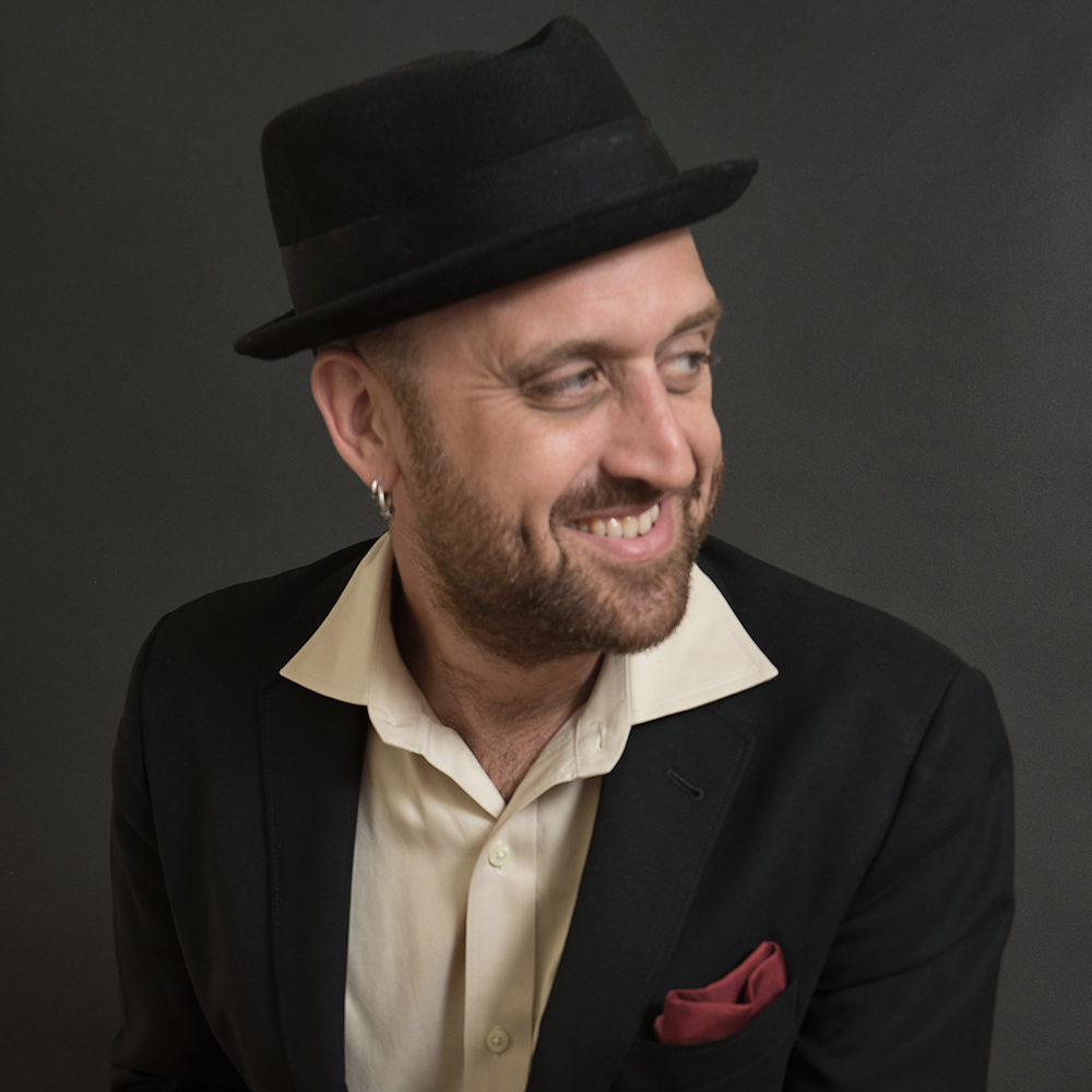 A speaker photo of a man in a brimmed hat.; A Reading with Franz Nicolay