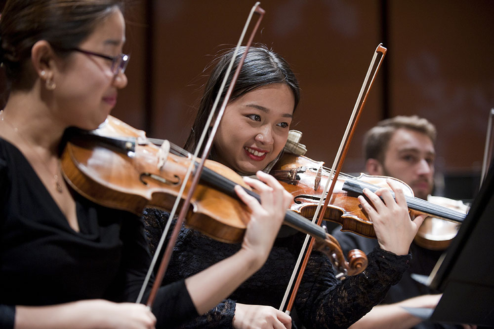 Students smile while playing violin during Bard's Winterfest concert.